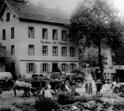 Das Foto aus dem Jahr um 1900 zeigt Personen und etliche Pferde- wie Ochsenkarren vor dem Hauptgebäude der Alten Schmelz.
